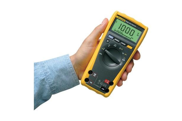 En person holder et gult Fluke 77 IV digitalt multimeter til el- og elektronikopgaver.