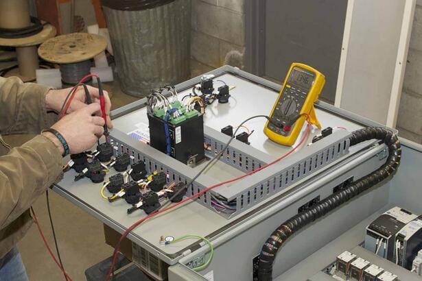 Tekniker udfører fejlfinding på industrielt el-panel med en Fluke 87V digital multimeter.