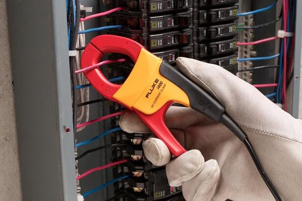 Tekniker måler strøm med en Fluke i400 strømtang på ledninger i et elskab.