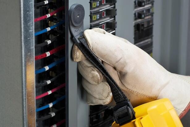 Tekniker bruger Fluke TPAK magnetisk ophængsrem til fastgørelse af multimeter på eltavle.